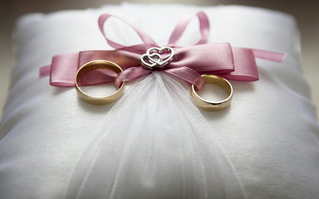 selective focus photography of silver colored engagement ring set with pink bow accent on throw pillow