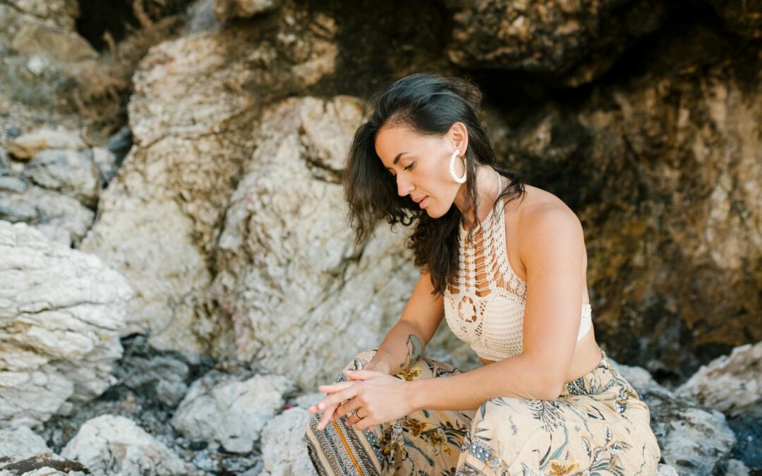 an attractive woman sitting on a rock looking down