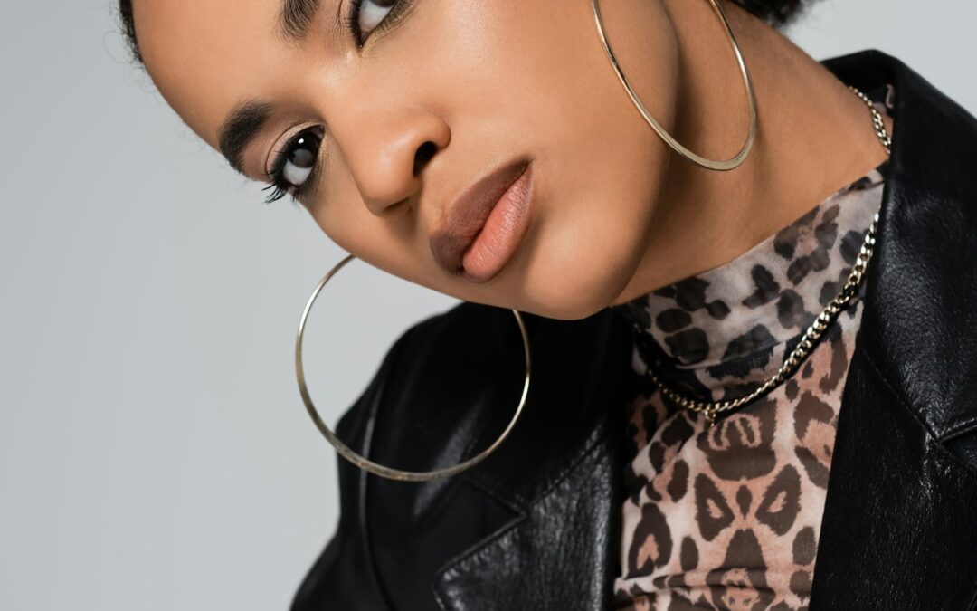 portrait of charming african american woman in trendy clothes and hoop earrings looking at camera